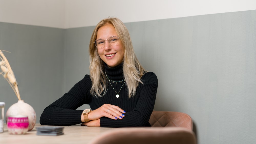 Anna Kamma - blonde girl in glasses sits at table smiling