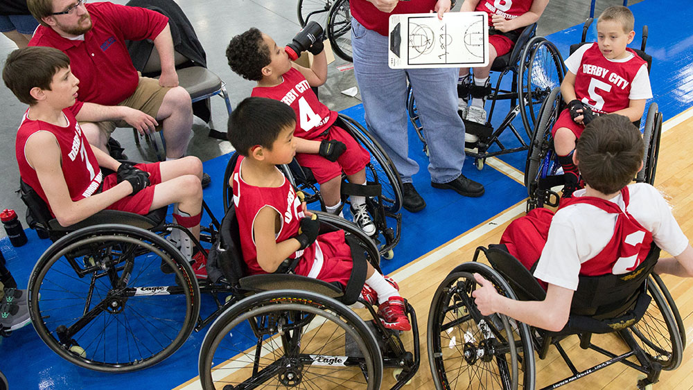 Young wheelchair basketball players receiving coaching