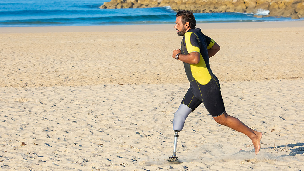 Man with prosthetic leg runs on beach 